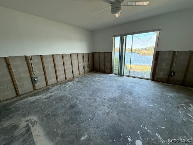 unfurnished room featuring a water view, ceiling fan, and concrete flooring