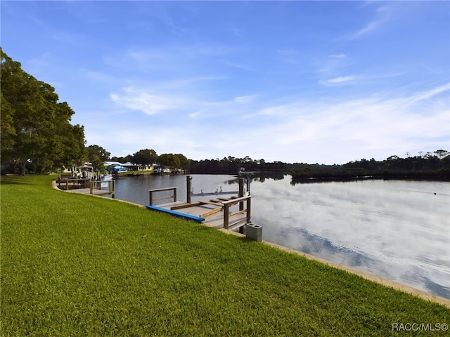 view of dock with a lawn and a water view