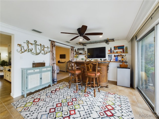 bar with ceiling fan, ornamental molding, and light tile patterned floors