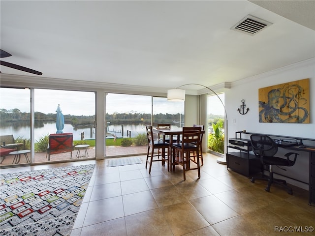 dining room featuring ornamental molding, a water view, a healthy amount of sunlight, and tile patterned floors