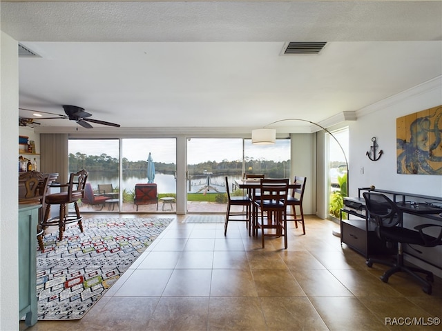 tiled dining space with plenty of natural light, ornamental molding, expansive windows, and a water view