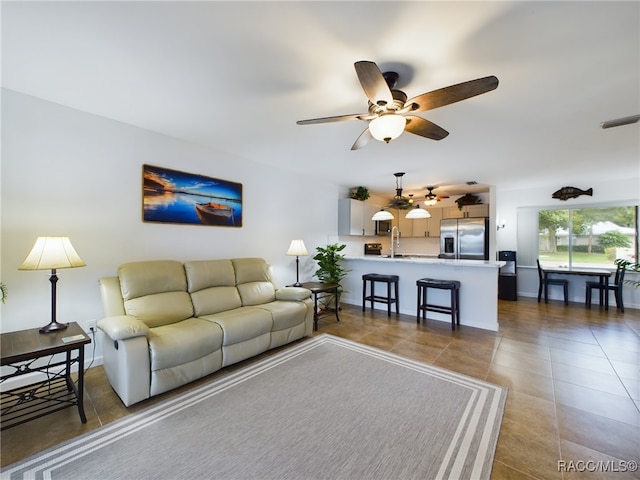 living room featuring light tile patterned floors, sink, and ceiling fan