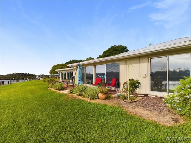 rear view of house with a water view and a yard