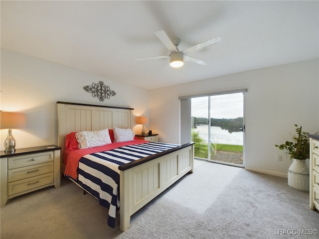 carpeted bedroom with access to exterior, ceiling fan, and a water view