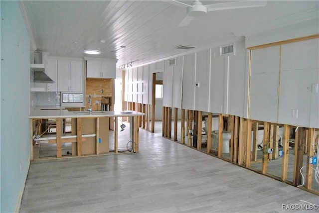 kitchen featuring white cabinets, sink, a kitchen island with sink, ceiling fan, and crown molding