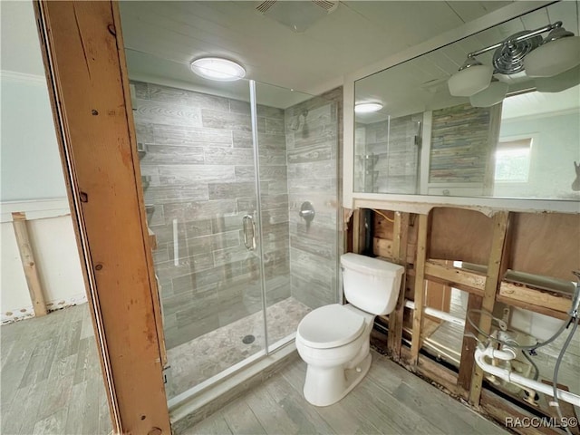 bathroom with toilet, a shower with shower door, and hardwood / wood-style flooring