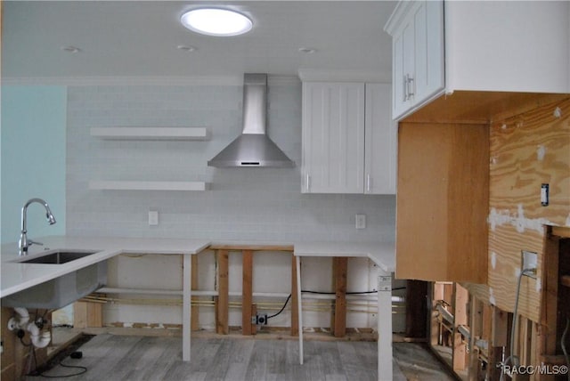 kitchen featuring tasteful backsplash, sink, hardwood / wood-style flooring, white cabinets, and wall chimney exhaust hood