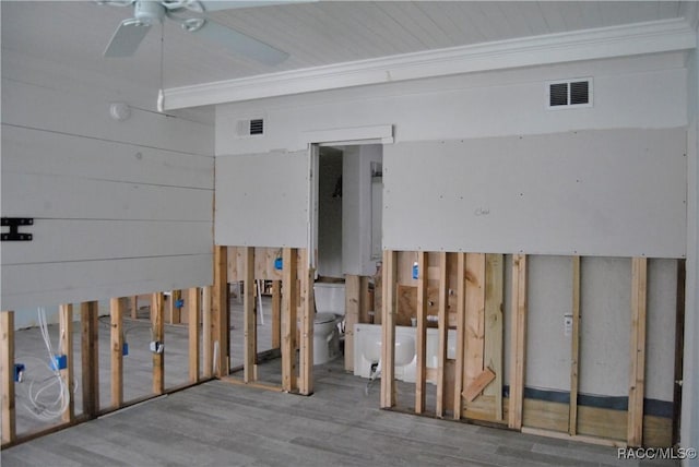 miscellaneous room with ceiling fan, wood-type flooring, and wood walls