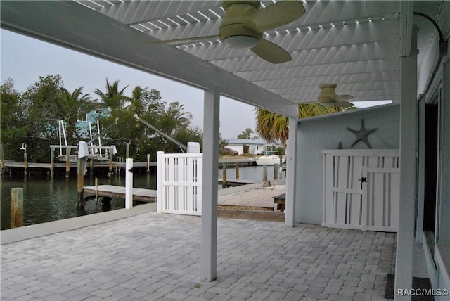 view of patio with ceiling fan, a water view, and a boat dock