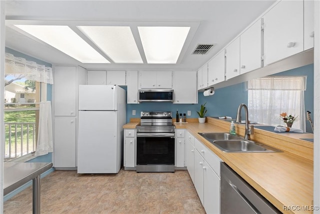 kitchen with appliances with stainless steel finishes, a wealth of natural light, a sink, and visible vents