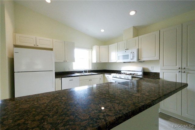 kitchen featuring vaulted ceiling, sink, white cabinets, dark stone counters, and white appliances