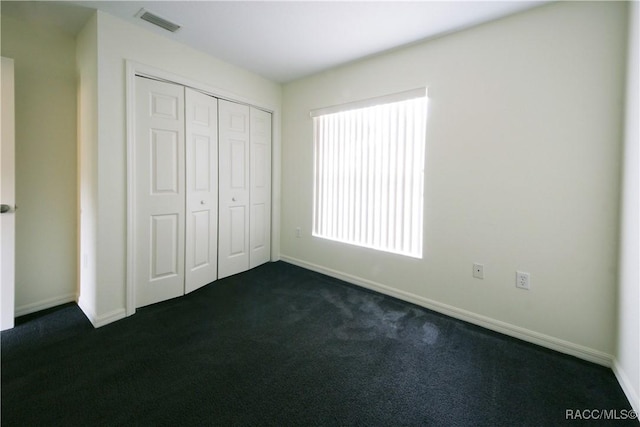 unfurnished bedroom featuring dark colored carpet and a closet