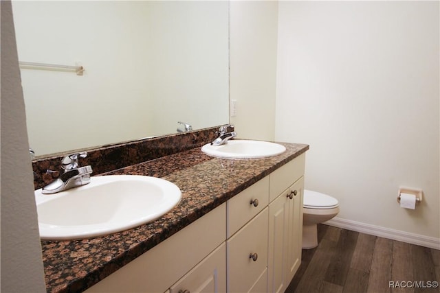 bathroom with wood-type flooring, vanity, and toilet