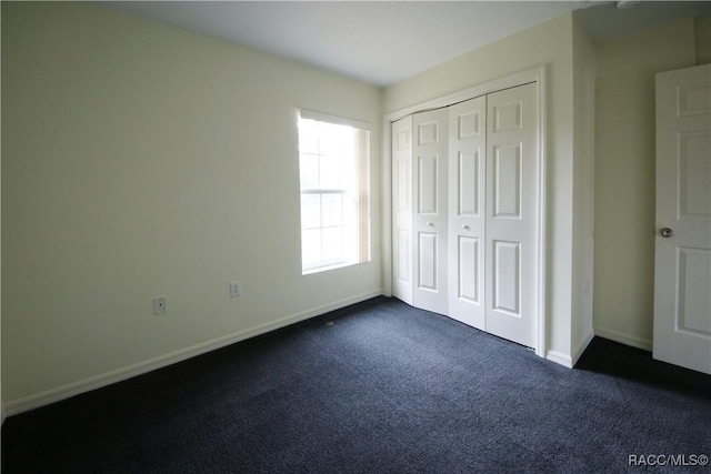 unfurnished bedroom with dark colored carpet and a closet