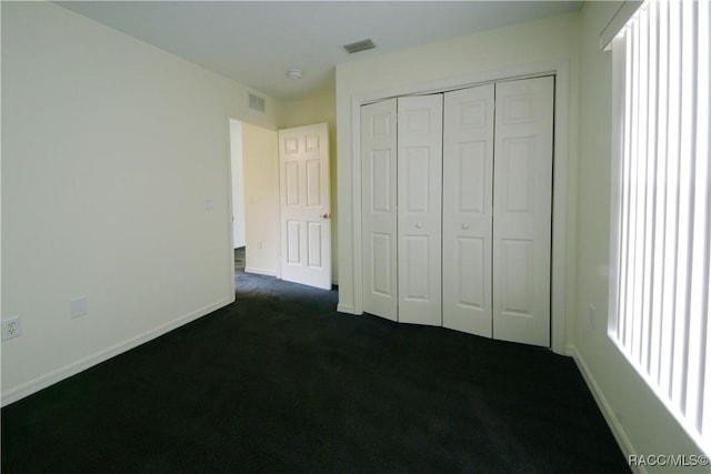 unfurnished bedroom featuring dark colored carpet and a closet