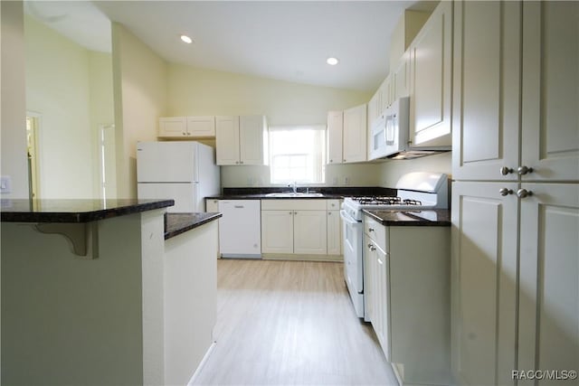 kitchen with vaulted ceiling, sink, white cabinets, a kitchen bar, and white appliances