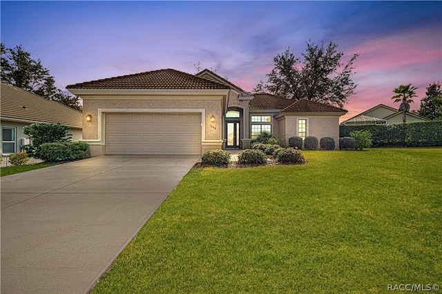 mediterranean / spanish house featuring a garage and a lawn