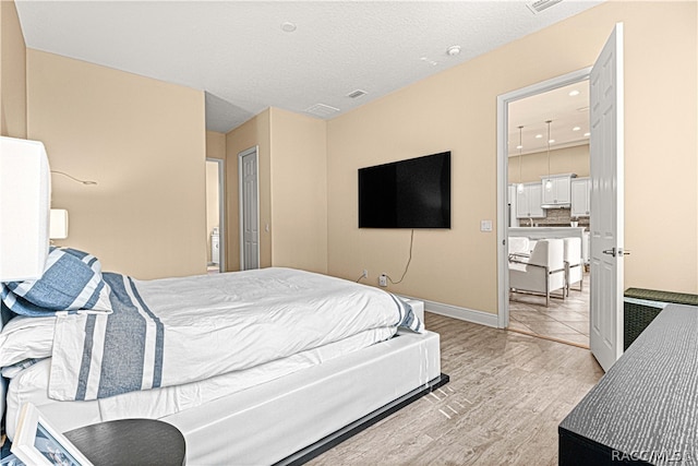 bedroom with a textured ceiling and light hardwood / wood-style floors