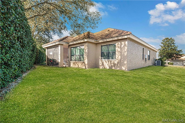 exterior space with central AC unit, a garage, and a lawn