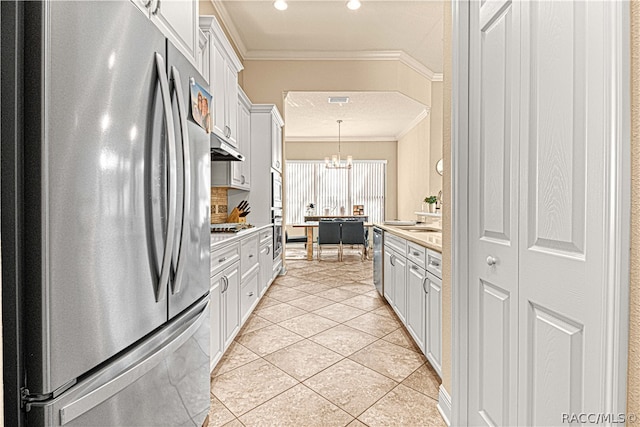 kitchen featuring crown molding, appliances with stainless steel finishes, decorative light fixtures, light tile patterned flooring, and white cabinetry