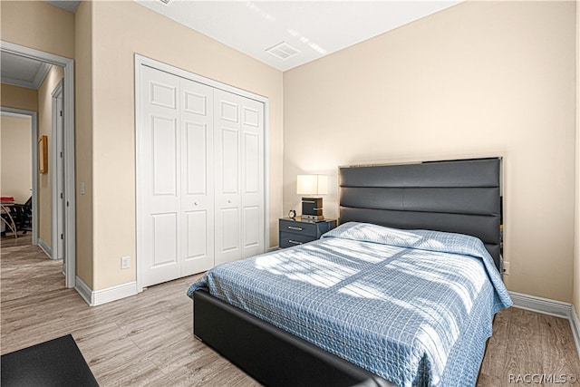 bedroom featuring crown molding, light hardwood / wood-style flooring, and a closet