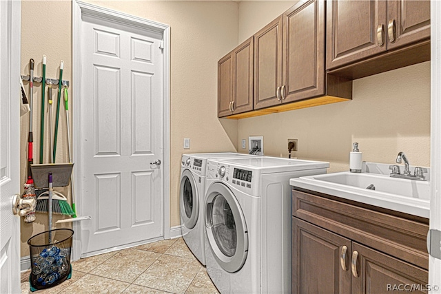 laundry room with cabinets, light tile patterned floors, washer and dryer, and sink