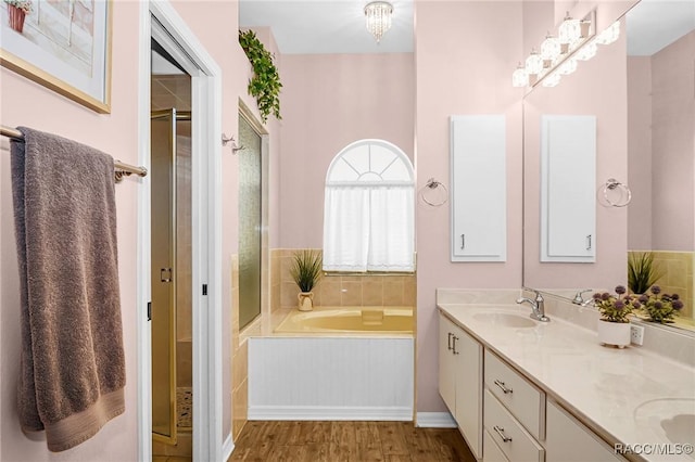 bathroom with hardwood / wood-style flooring, vanity, tiled bath, and a chandelier