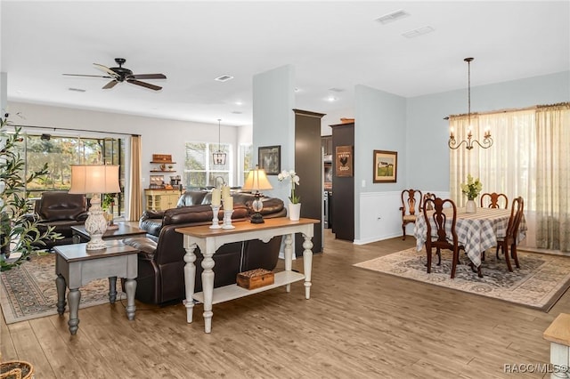 living room with ceiling fan with notable chandelier and wood-type flooring