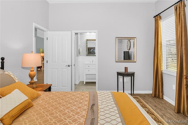 bedroom with light wood-type flooring and connected bathroom