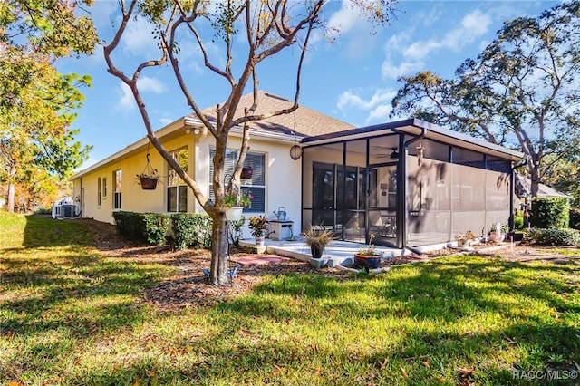 rear view of house with a sunroom, a yard, and central air condition unit