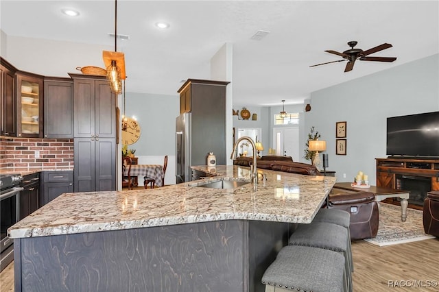 kitchen with dark brown cabinetry, light hardwood / wood-style floors, hanging light fixtures, and sink