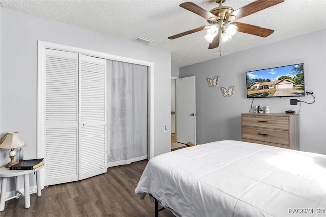 bedroom with dark hardwood / wood-style flooring, a textured ceiling, ceiling fan, and a closet