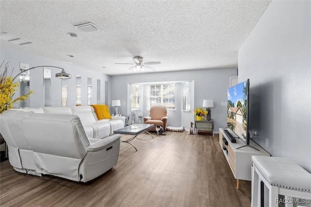 living room featuring ceiling fan, wood-type flooring, and a textured ceiling