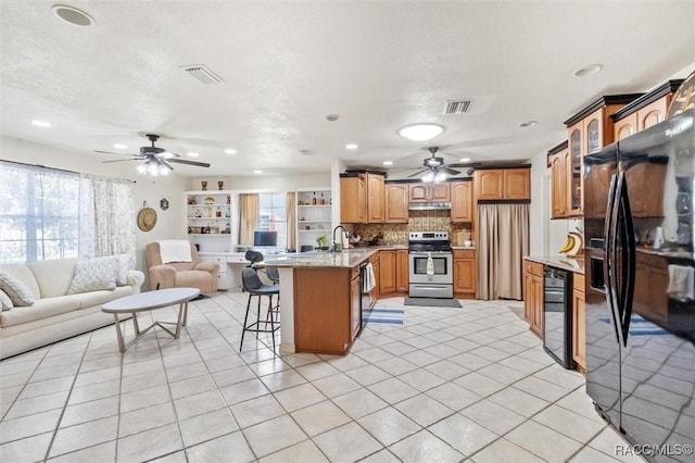 kitchen featuring a breakfast bar, black fridge, a textured ceiling, electric range, and decorative backsplash