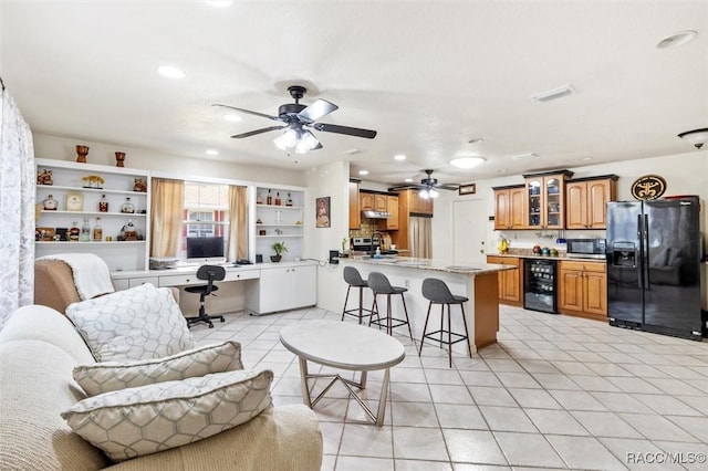 tiled living room with built in features, built in desk, wine cooler, and ceiling fan