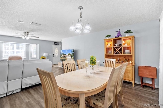 dining room featuring dark hardwood / wood-style flooring, ceiling fan with notable chandelier, and a textured ceiling