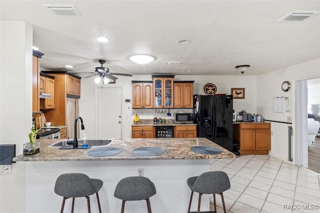 kitchen featuring sink, beverage cooler, a kitchen bar, kitchen peninsula, and black refrigerator with ice dispenser