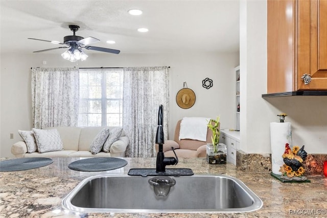 kitchen featuring light stone countertops, sink, and ceiling fan