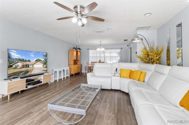 living room featuring dark hardwood / wood-style floors, ceiling fan with notable chandelier, and a textured ceiling