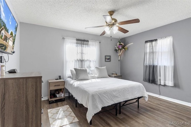 bedroom with a textured ceiling, dark hardwood / wood-style floors, and ceiling fan