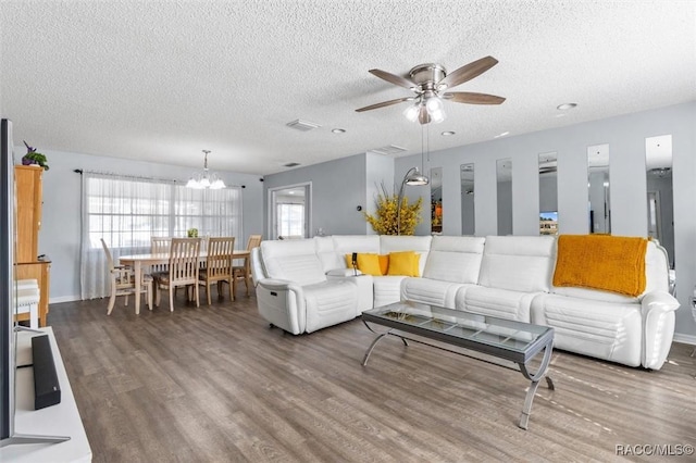 living room featuring hardwood / wood-style flooring, ceiling fan with notable chandelier, and a textured ceiling