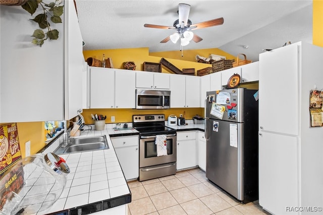 kitchen featuring light tile patterned flooring, appliances with stainless steel finishes, white cabinetry, sink, and tile counters