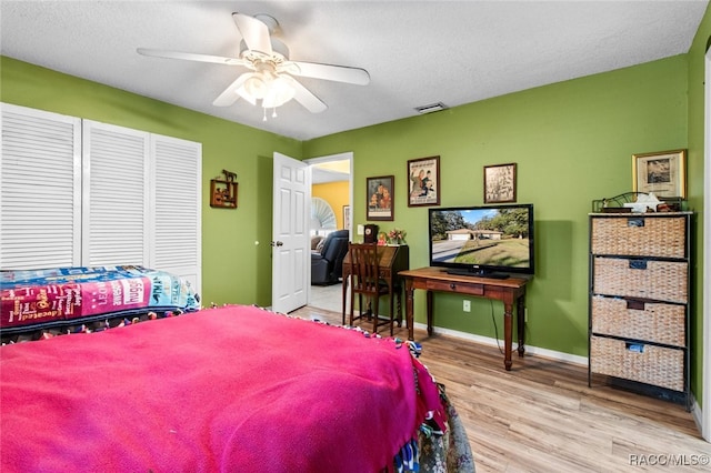 bedroom with ceiling fan, light hardwood / wood-style flooring, and a textured ceiling