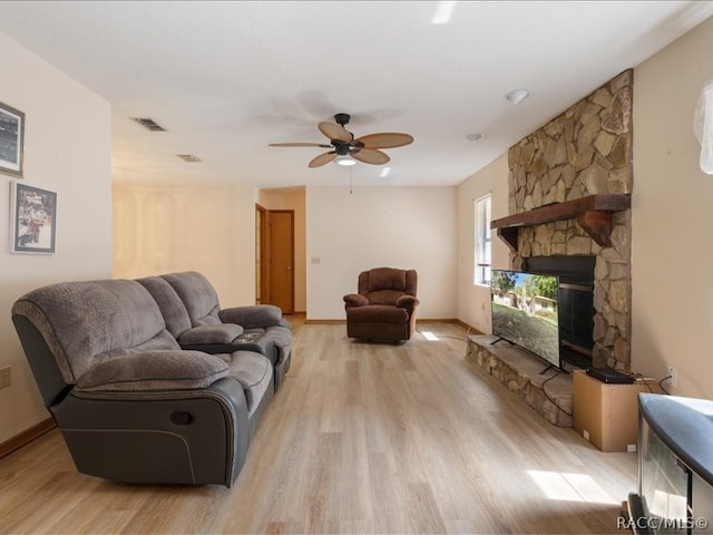 living room with ceiling fan, a fireplace, and light hardwood / wood-style floors