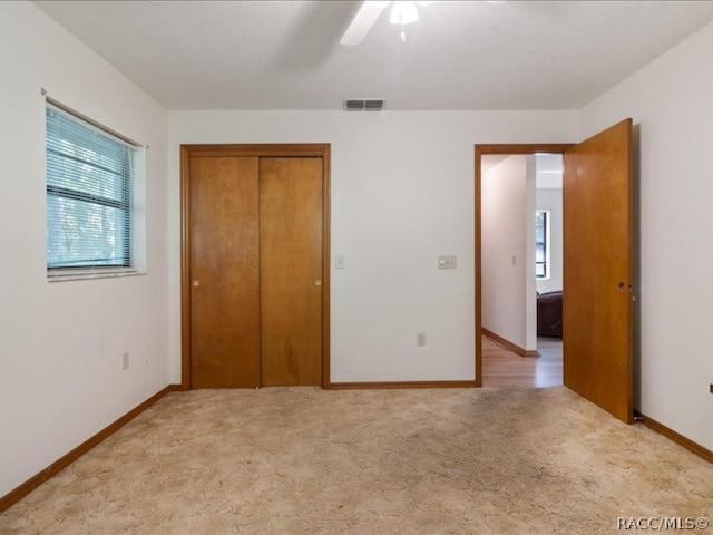 unfurnished bedroom with ceiling fan, a closet, and light carpet