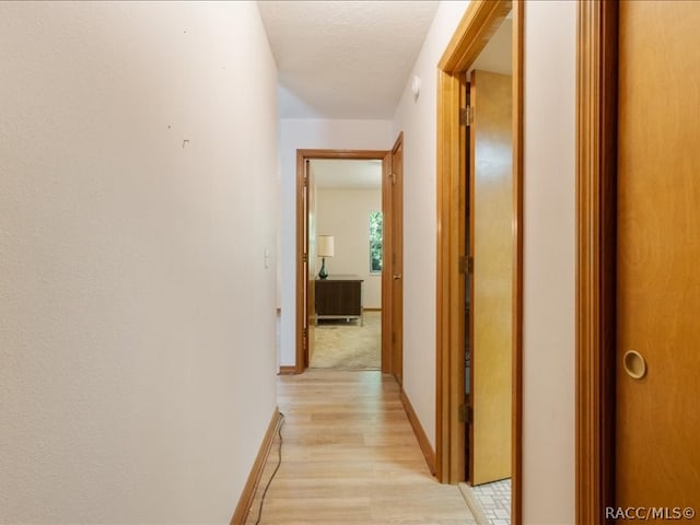 hall featuring light hardwood / wood-style flooring and a textured ceiling