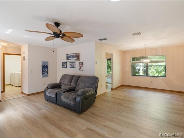 living room featuring ceiling fan with notable chandelier and light hardwood / wood-style flooring