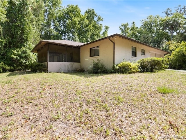 view of property exterior with a lawn and a sunroom