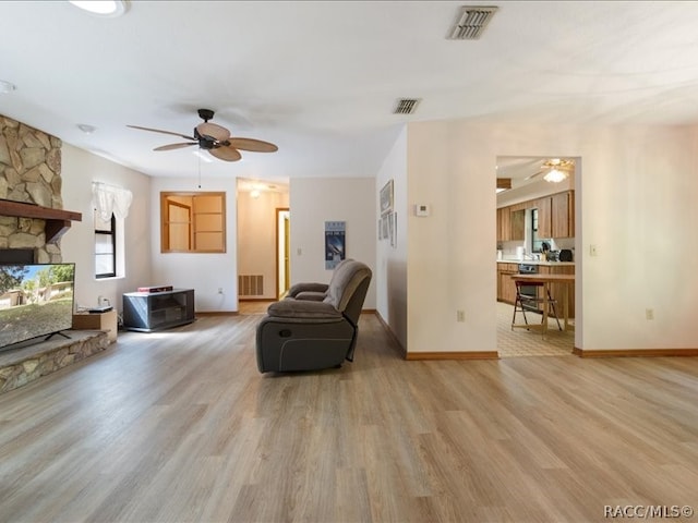 living room with ceiling fan, a fireplace, and light wood-type flooring