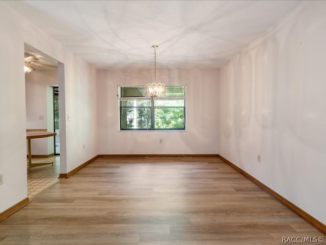 unfurnished dining area featuring ceiling fan with notable chandelier and light hardwood / wood-style floors